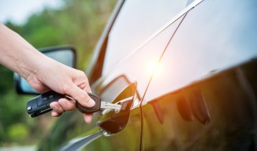 Woman hand inserting key in car door.